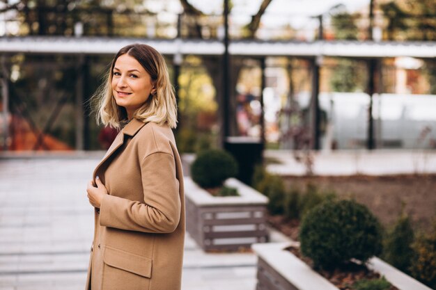 Belle femme dans un manteau beige à l'extérieur dans le parc