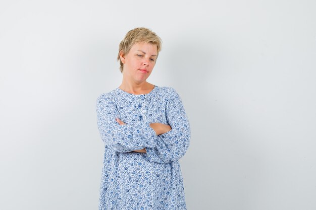 Belle femme debout avec les bras croisés en chemisier à motifs et à la recherche offensée. vue de face.