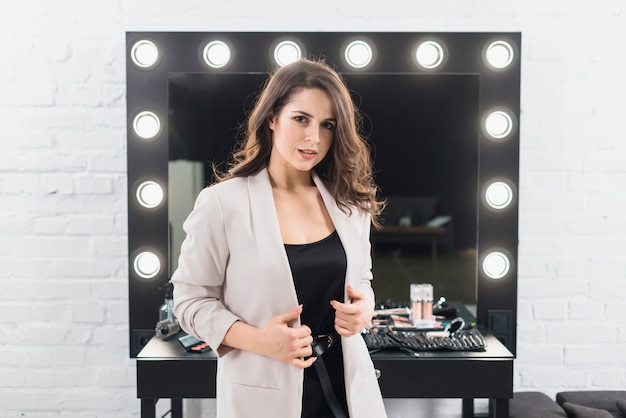 Photo gratuite belle femme debout contre un miroir de maquillage