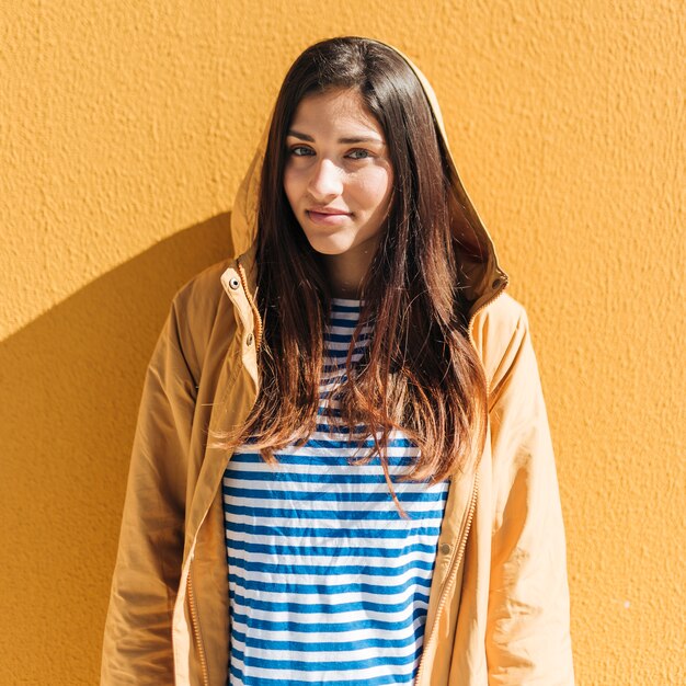 Belle femme debout contre le mur jaune