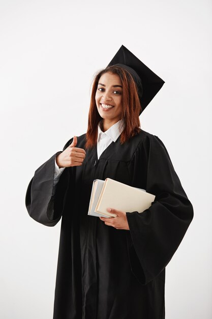 Belle femme diplômée africaine heureuse souriant montrant bien tenir des livres.