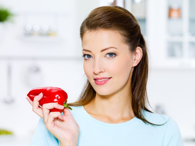 Belle femme avec du poivron rouge sur la cuisine