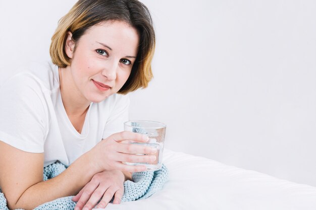 Belle femme avec de l&#39;eau allongée sur le lit