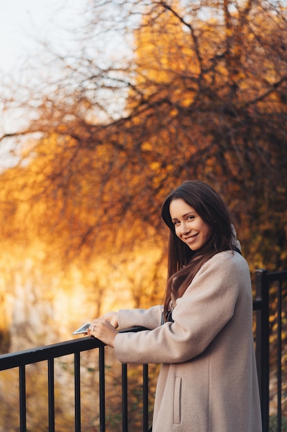 Belle femme élégante, debout dans un parc en automne