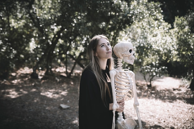 Photo gratuite belle femme embrassant derrière le squelette