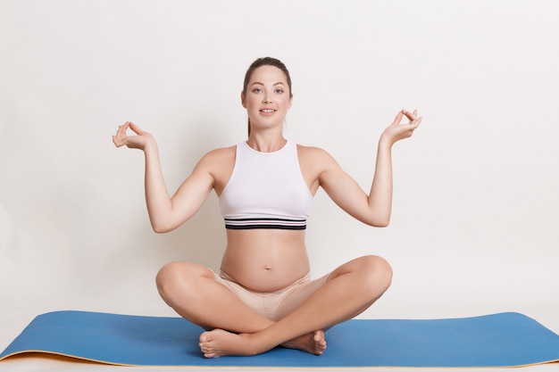 Photo gratuite belle femme enceinte faisant du yoga à la maison