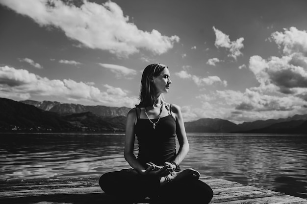 Belle femme enceinte en vêtements noirs est assis sur le pont en bois sur le lac