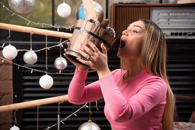 Belle femme essayant de manger un seau de pommes de pin à la maison.