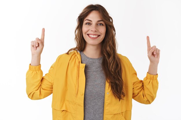 Une belle femme européenne frisée et pleine d'énergie pointant les mains vers le haut montrant une nouvelle promo cool souriante à pleines dents partageant joyeusement un lien intéressant recommander un produit d'essai tourner l'attention vers le haut