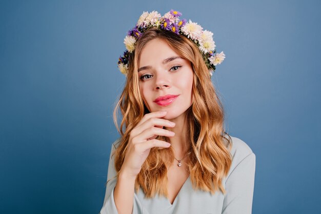 Belle femme européenne à la peau pâle posant sur un mur bleu foncé