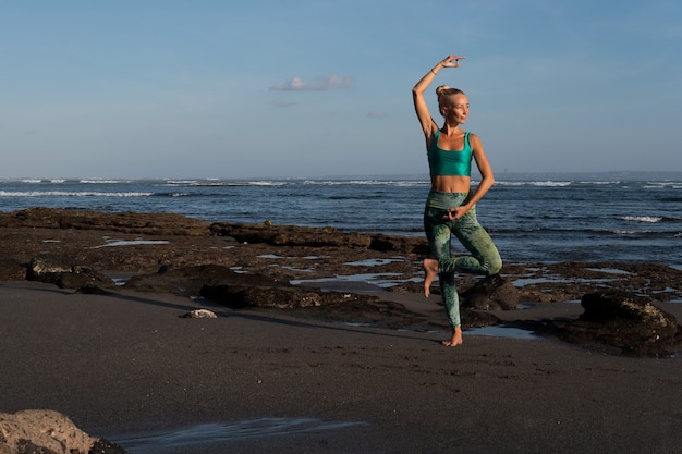 Belle femme faisant du yoga sur la plage