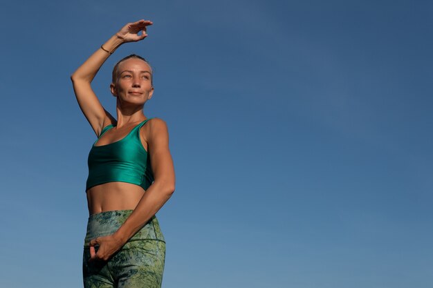 Belle femme faisant du yoga sur la plage