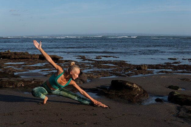 Belle femme faisant du yoga sur la plage