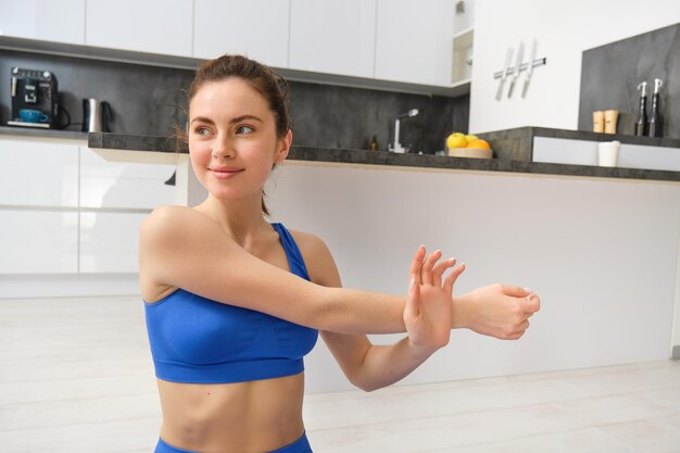 Photo gratuite une belle femme en forme s'entraîne à la maison, étirent ses bras, s'échauffent avant l'entraînement.