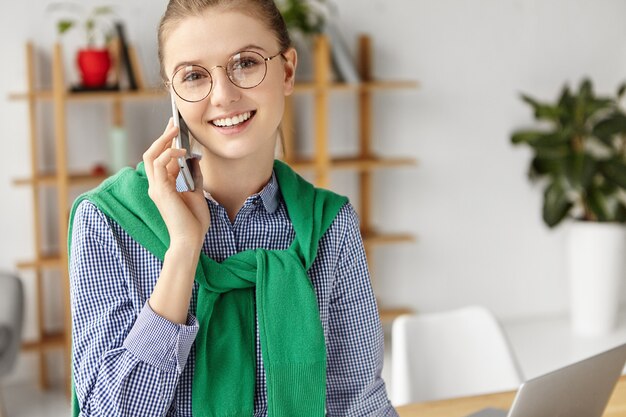 Belle femme habillée officiellement au bureau avec téléphone