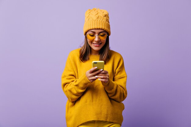 Belle femme heureuse aime la couleur jaune et porte une tenue jaune totale. snapportrait de belle fille bavardant dans son smartphone