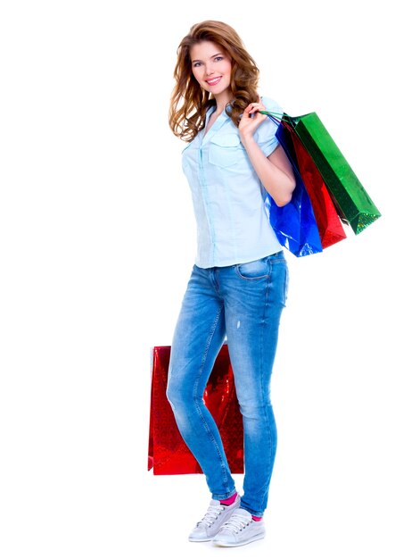 Belle femme heureuse avec des sacs à provisions en jean bleu isolé sur fond blanc