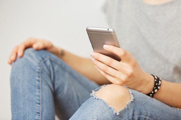 Belle femme hipster vérification des e-mails via téléphone mobile tandis que mur gris