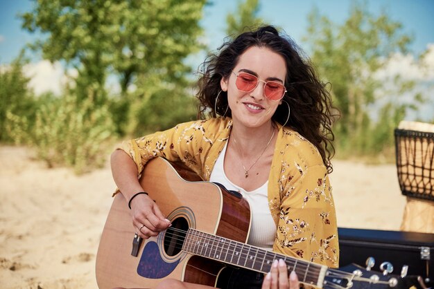 Belle femme jouant de la guitare sur la plage