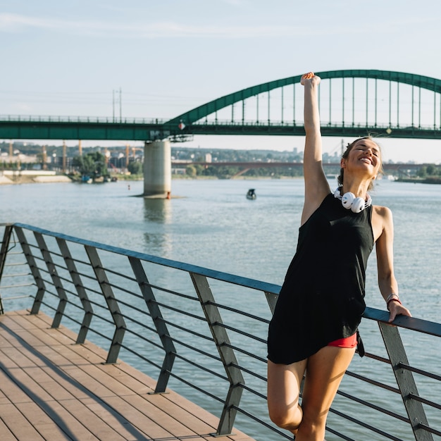 Photo gratuite belle femme levant ses bras debout près de la rivière