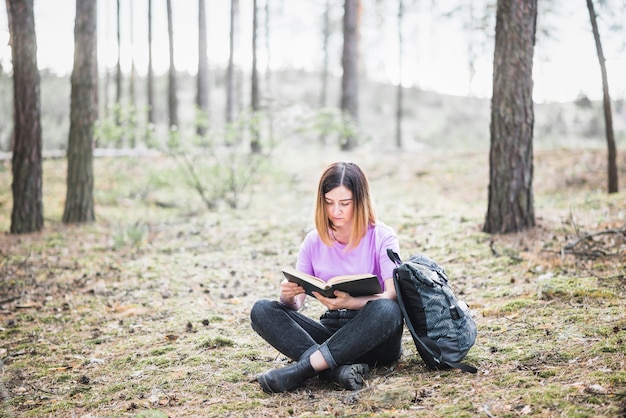Photo gratuite belle femme lisant un livre dans la forêt