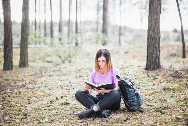 Belle femme lisant un livre dans la forêt