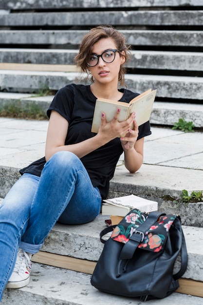 Photo gratuite belle femme avec livre allongé sur les escaliers