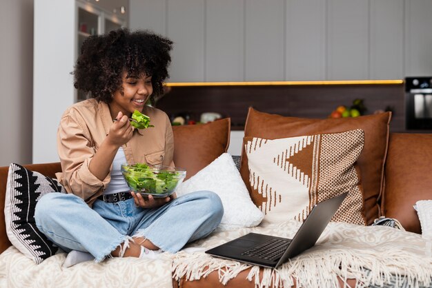 Belle femme mangeant de la salade sur un canapé