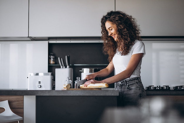 Belle femme, manger du pain frais à la cuisine