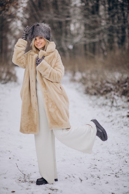 Belle femme marchant dans un parc plein de neige
