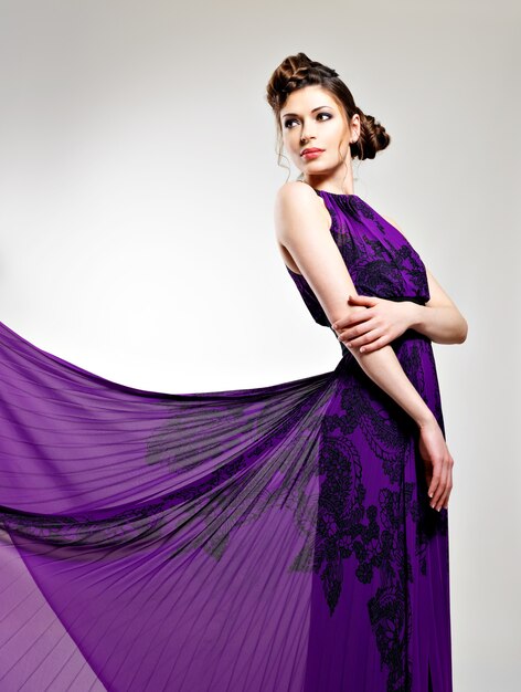 Belle femme de mode en coiffure robe longue violette avec conception de tresses, pose au studio