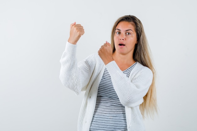 Belle femme montrant le geste gagnant en veste et à la surprise. vue de face.