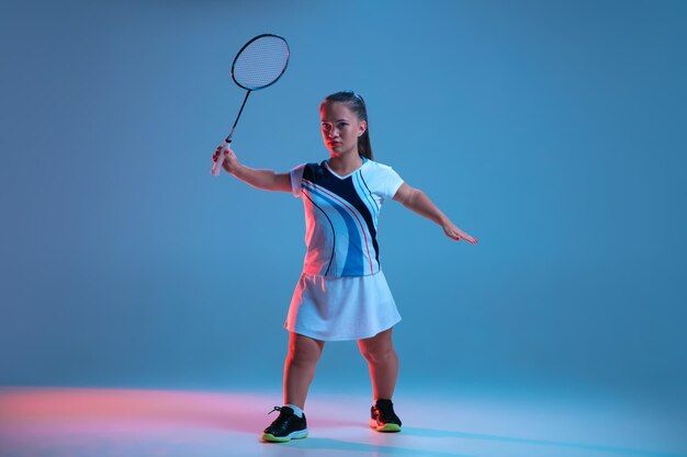 Belle femme naine pratiquant le badminton isolé sur bleu en néon