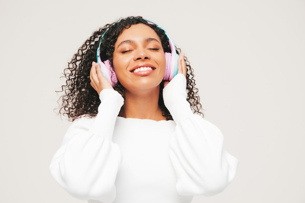 Belle femme noire avec une coiffure de boucles afro. Modèle souriant en pull et jeans