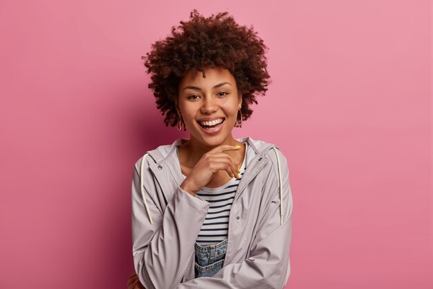 Belle femme optimiste avec une coiffure afro, porte un anorak décontracté