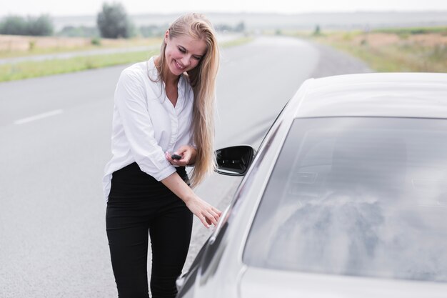 Belle femme ouvrant la porte de la voiture