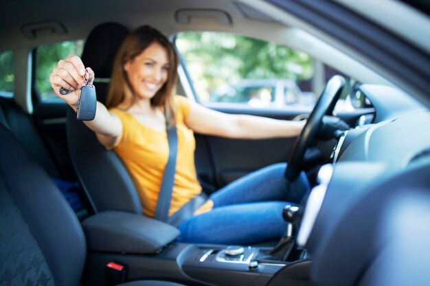 Belle femme pilote assis dans son véhicule et tenant des clés de voiture prêtes pour un lecteur