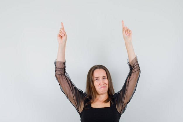 Belle femme pointant vers le haut en chemisier noir et à la mécontentement