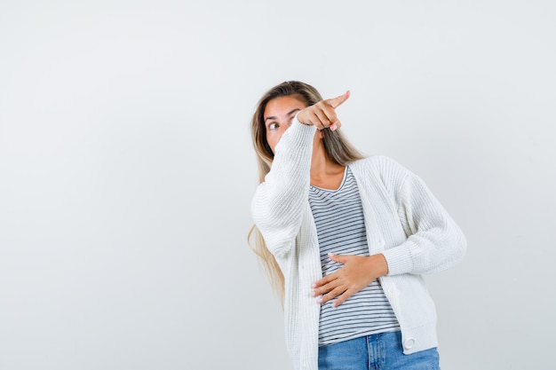 Belle femme pointant vers quelque chose dans la veste et l'air concerné. vue de face.