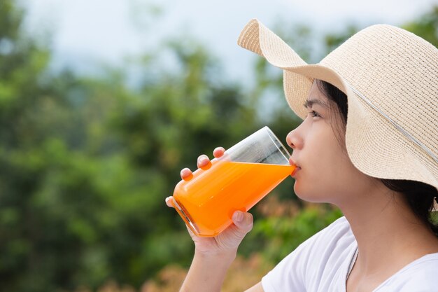 Belle femme portant un t-shirt blanc tenant un verre de jus d'orange