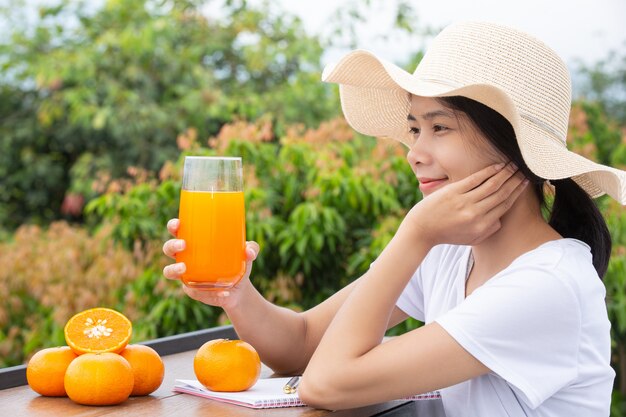 Belle femme portant un t-shirt blanc tenant un verre de jus d'orange