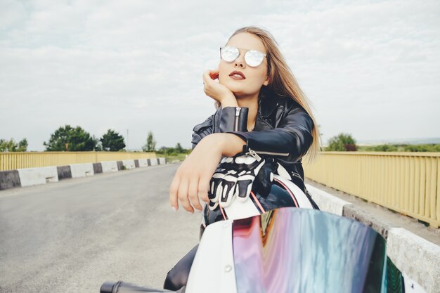 Belle femme posant avec des lunettes de soleil sur une moto