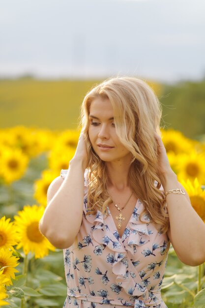 Belle femme pose dans le domaine agricole avec tournesol sur une journée d'été ensoleillée