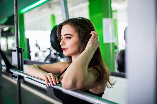 Belle femme pose en sportclub avec haltères