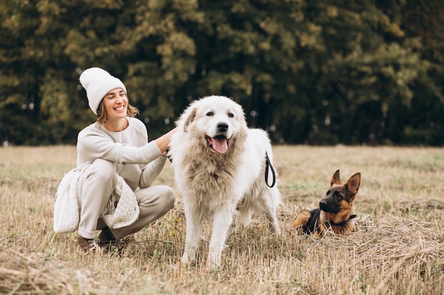 Photo gratuite belle femme promenant ses chiens dans un champ