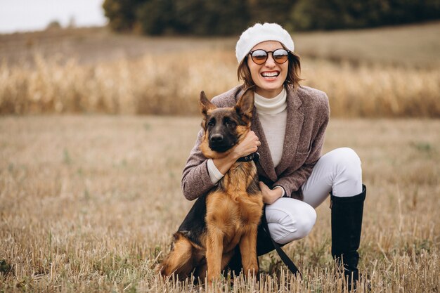 Belle femme promenant son chien dans un champ