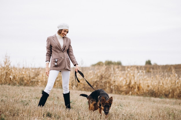 Belle femme promenant son chien dans un champ