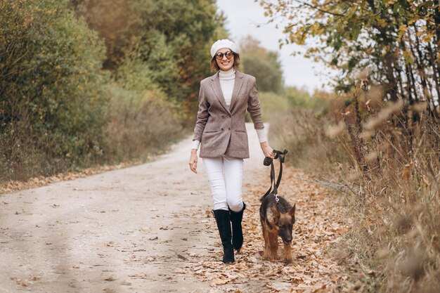 Belle femme promenant son chien dans un parc en automne