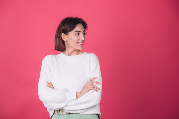 Belle femme en pull blanc décontracté sur mur rouge