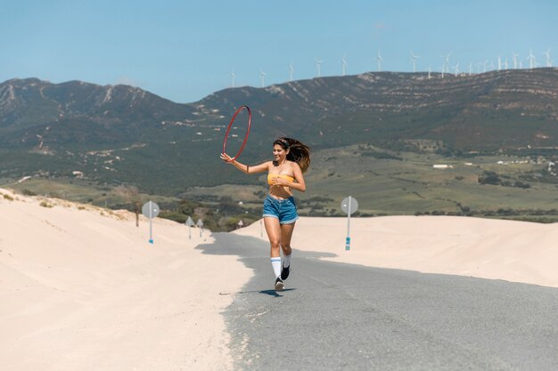 Belle femme qui court avec cerceau sur le sable